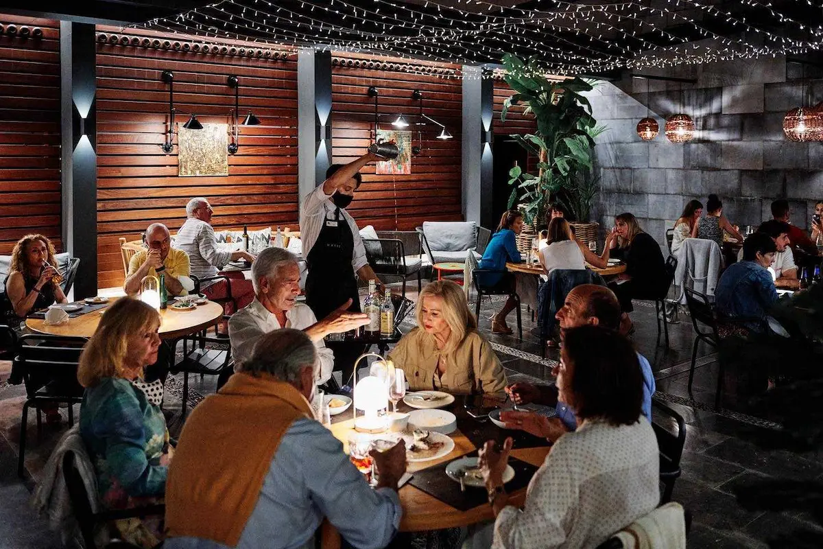 Gente disfrutando de la terraza y de la comida en el restaurante Cañadú de Málaga