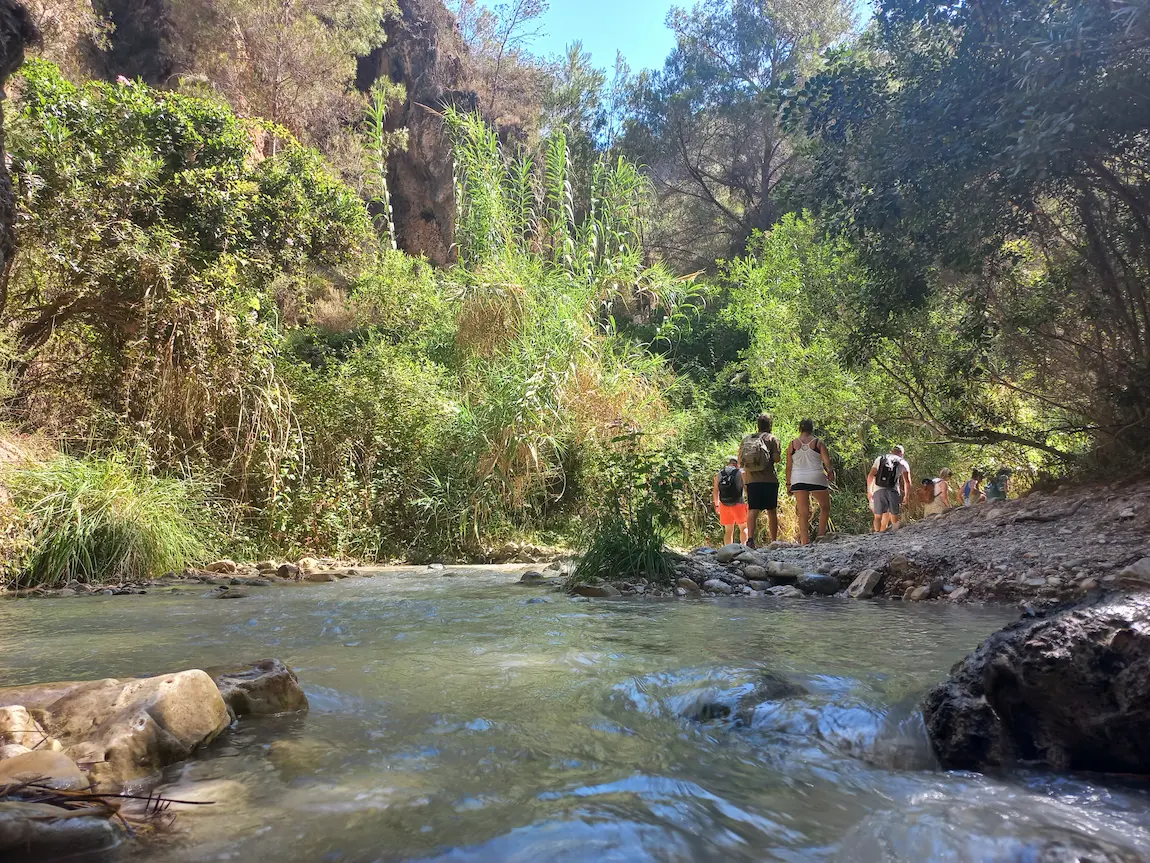 Passage längs floden Rio Chillar omgiven av vegetation, med vandrare som gör resan